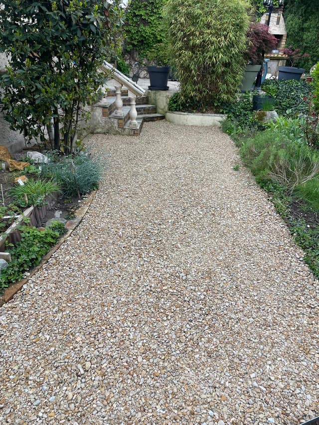 Allée en gravillon terminée dans un jardin paysager avec escalier en pierre